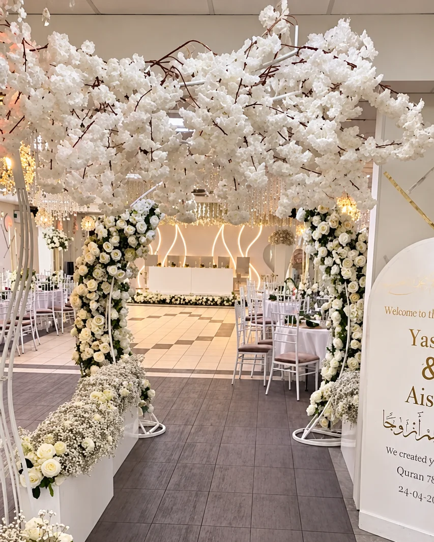 Jubbas eventlokal i Kista: blombågar av vita rosor under vita körsbärsblommor, in mot festsalen med scen och ljusvägg